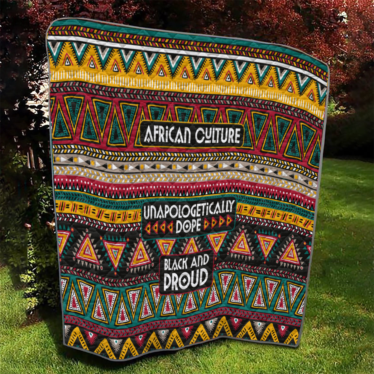 Colorful African-pattern quilt with bold geometric shapes and stacked slogans: “Unapologetically” and “Black and Proud.”