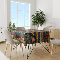 Rectangular geometric African patterned tablecloth in black, teal, maroon and yellow on a dining table