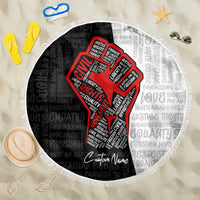 Round beach blanket with fringed edge, black base with red justice-fist word art and patterned text