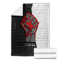 Gray blanket with red justice fist graphic, repeating text pattern, folded with custom name