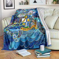 Blue Anguilla blanket with sea turtle, ocean shell artwork, and scalloped scale pattern.