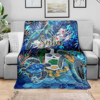 Blue sea turtle blanket draped on gray sofa, tropical Saba design