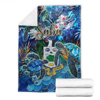 Blue sea turtle blanket with tropical Saba design, folded with white towels