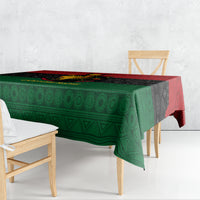 Tablecloth draped on wooden dining table, green geometric pattern with red edge