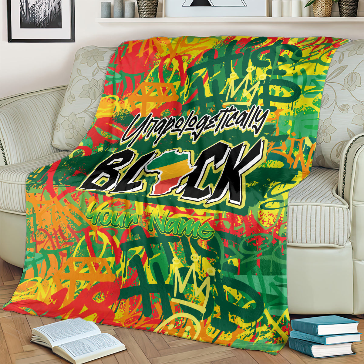Personalized throw blanket on a couch, green with red-orange artwork and bold black BLK typography.