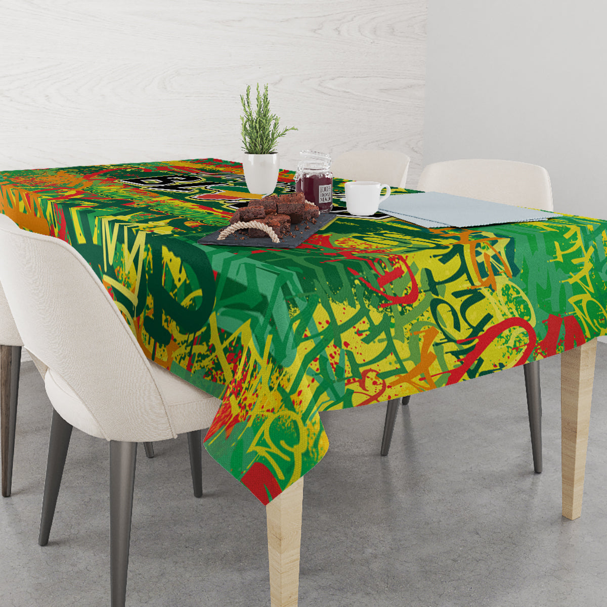 Green and red graffiti-style tablecloth on dining table with dishes and decor