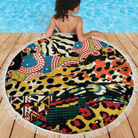 Round beach blanket with fringe edge, vibrant animal-pattern graphic on outdoor wood.