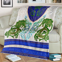Dragon celtic knot throw blanket draped on a sofa, green and blue pattern on cream