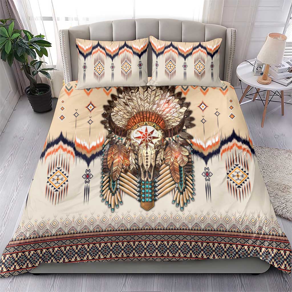 Beige bedding set with central feathered skull print, patterned pillows, navy and orange trim