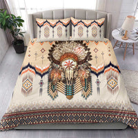 Beige bedding set with central feathered skull print, patterned pillows, navy and orange trim