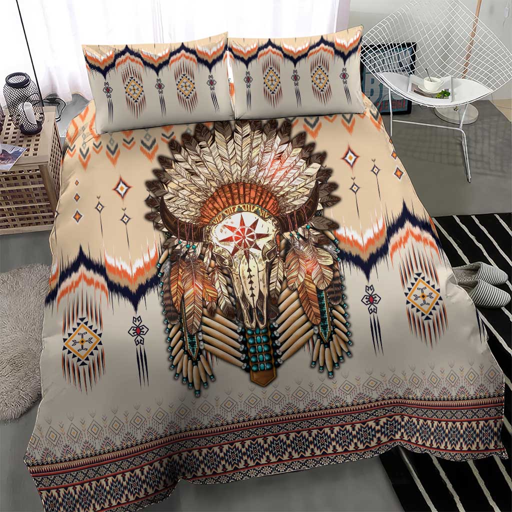 Beige duvet and two pillows with feathered skull artwork, navy, orange, and diamond designs