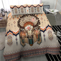Beige duvet and two pillows with feathered skull artwork, navy, orange, and diamond designs