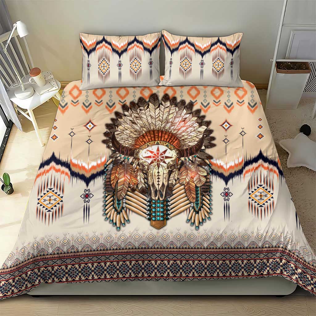 Beige bedding set with feathered skull centerpiece, two pillows, navy and orange southwestern border