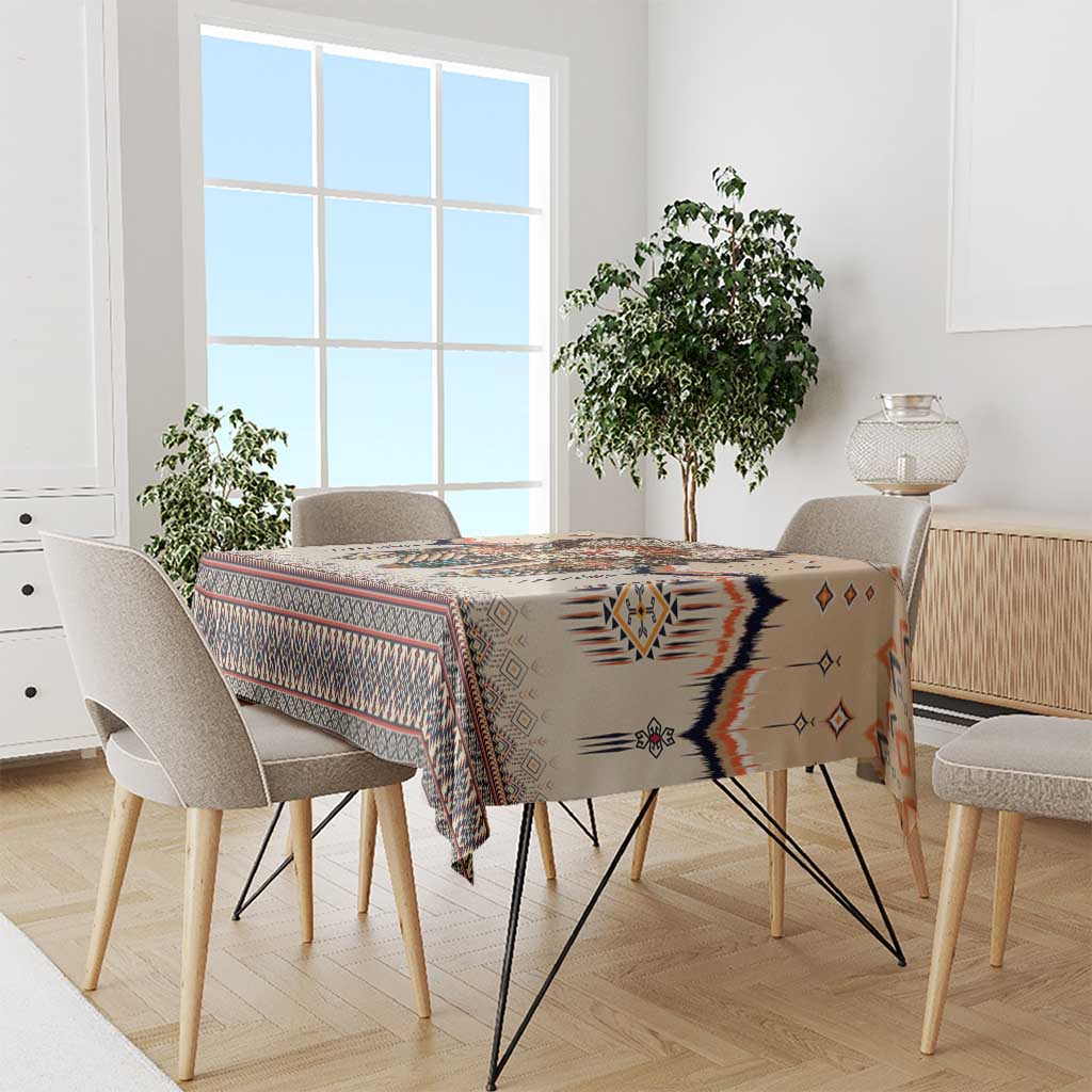 Beige tablecloth on dining table with multicolor Native American geometric pattern and border.