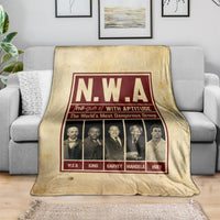 Beige group blanket draped on sofa showing N.W.A burgundy framed graphic and portraits