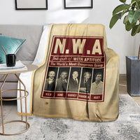 Beige group blanket on floor featuring N.W.A burgundy framed graphic and portraits