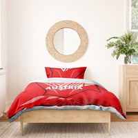 Red duvet cover and pillowcase with Austria text, over bed with geometric stripe pattern