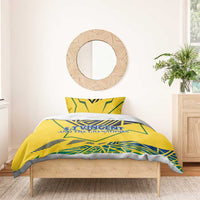 Yellow bedding set with duvet cover and two pillowcases, blue-green emblem text centered.