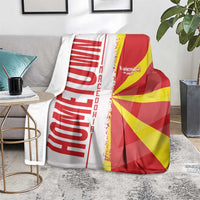 Macedonia flag and map blanket on gray sofa, red/yellow flag with bold white lettering