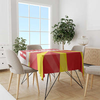 Red and yellow geometric flag tablecloth draped over dining table with chairs