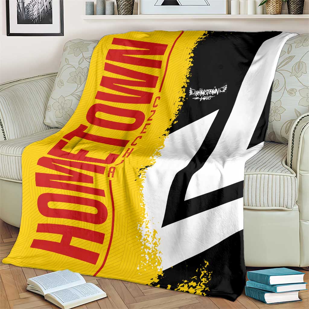 Yellow and black Germany flag blanket with white cross detail, draped over sofa
