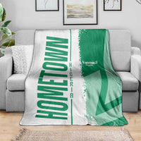 Green and white Nigeria flag and map blanket over gray couch