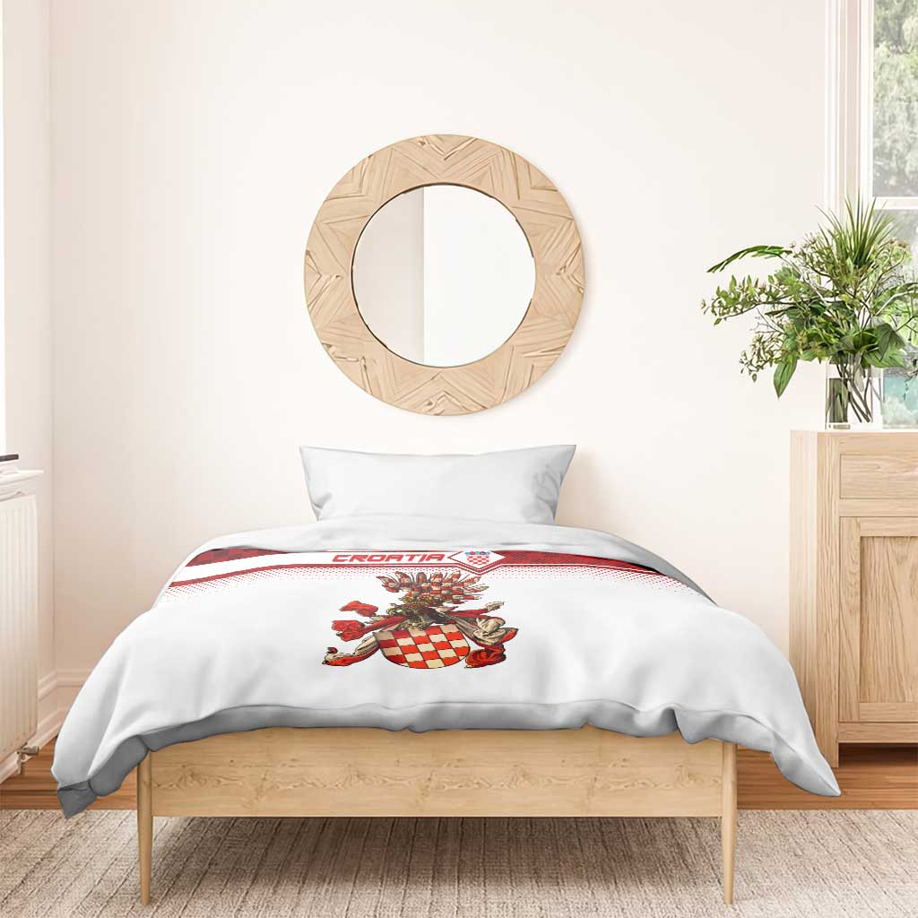 White duvet with red check crest design and two pillowcases on wooden bed