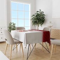 Red-and-black check tablecloth with central crest and white border, draped over dining table.