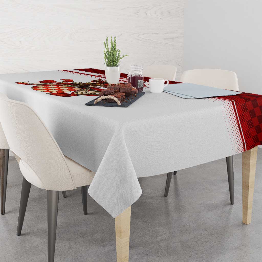 Rectangular white tablecloth with red check edge and crest design on tabletop.