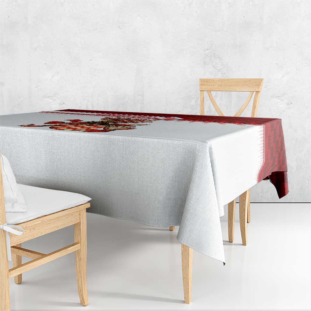 Tablecloth with red check border and crest print along the top edge, laid over dining bench.