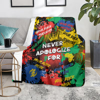 Multicolor printed throw blanket with large white lettering, draped on gray sofa
