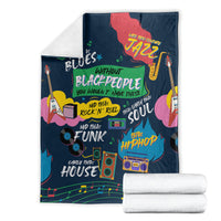 Folded dark blue African blanket with colorful music-themed artwork, stacked with white towels