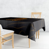 Black tablecloth draped over dining table with gold swirl pattern