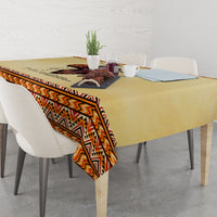 Beige tablecloth with orange and black geometric patterned border over dining table
