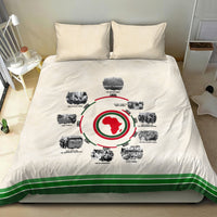 Beige bedding set on bed: duvet with circular African timeline graphic and green stripe border