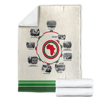 Cream history timeline blanket with red African map circle, shown with folded blanket stack