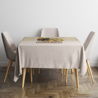 Beige tablecloth on square table with gold geometric border and centerpiece on top