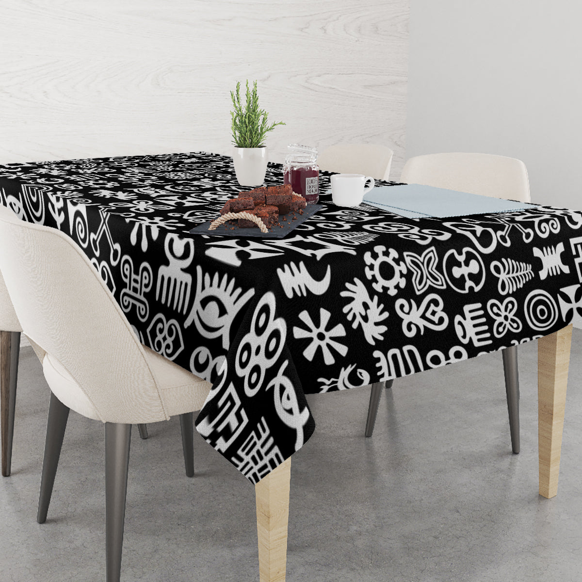 Black tablecloth with white adinkra-style symbols, draped over dining table