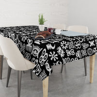 Black tablecloth with white adinkra-style symbols, draped over dining table