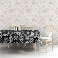 Black tablecloth with white adinkra motifs covering dining table, side view