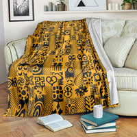 Yellow and black Adinkra pattern throw blanket draped on sofa