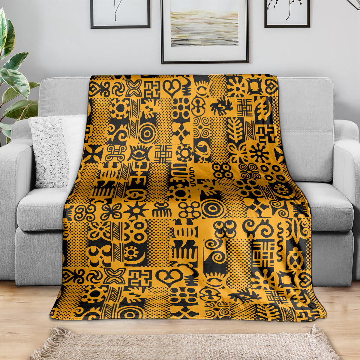 Yellow and black Adinkra pattern throw blanket spread on gray sofa