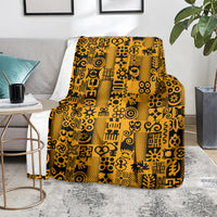 Yellow and black Adinkra pattern throw blanket on gray sofa with side decor