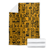 Yellow and black Adinkra pattern throw blanket folded with white towels