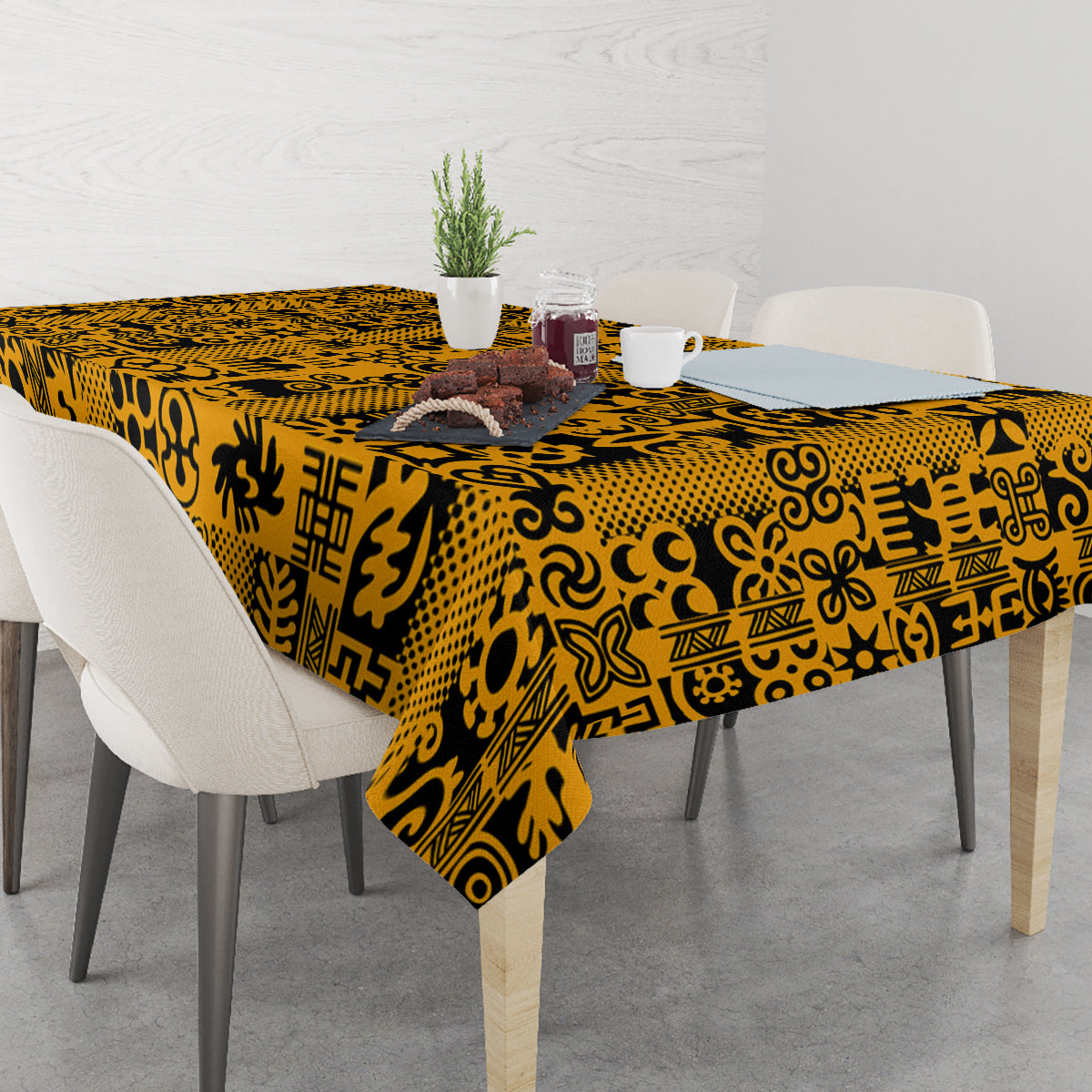 Yellow Adinkra tablecloth with black geometric motifs, spread across a dining table