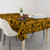 Yellow Adinkra tablecloth with black geometric motifs, spread across a dining table