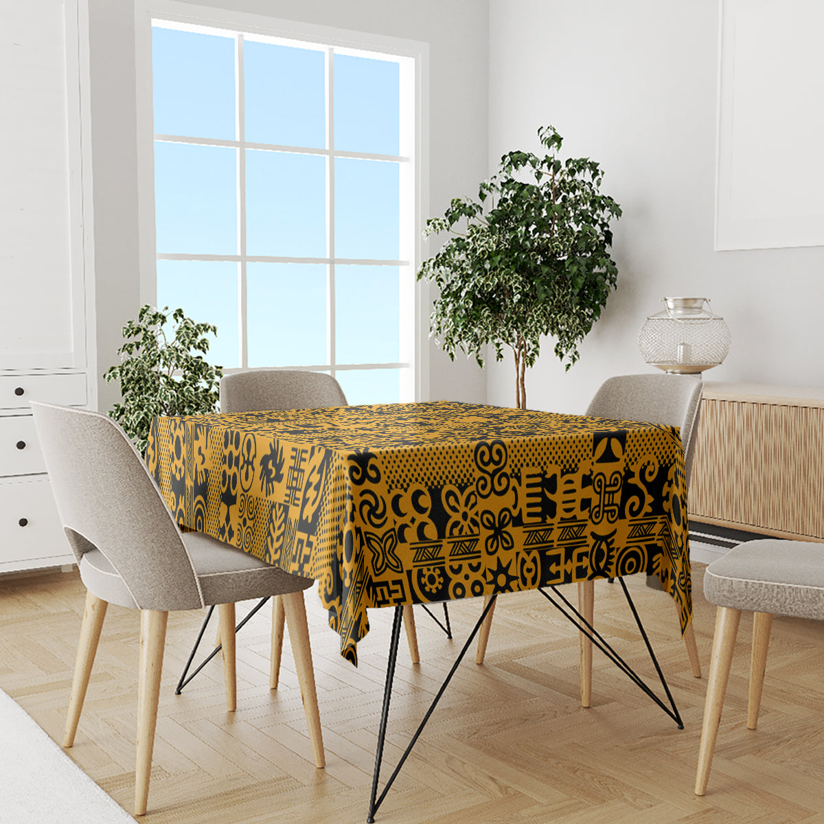 Yellow tablecloth with black Adinkra design, covering a dining table with chairs