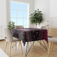 Black patterned Christmas tablecloth with pink and red trim design on dining table.