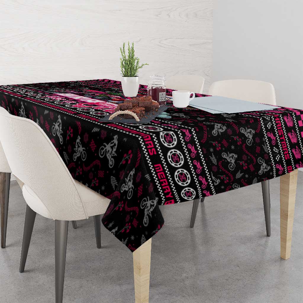 Black Christmas tablecloth with bold pink and red geometric border pattern over table.