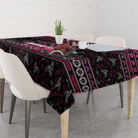 Black Christmas tablecloth with bold pink and red geometric border pattern over table.